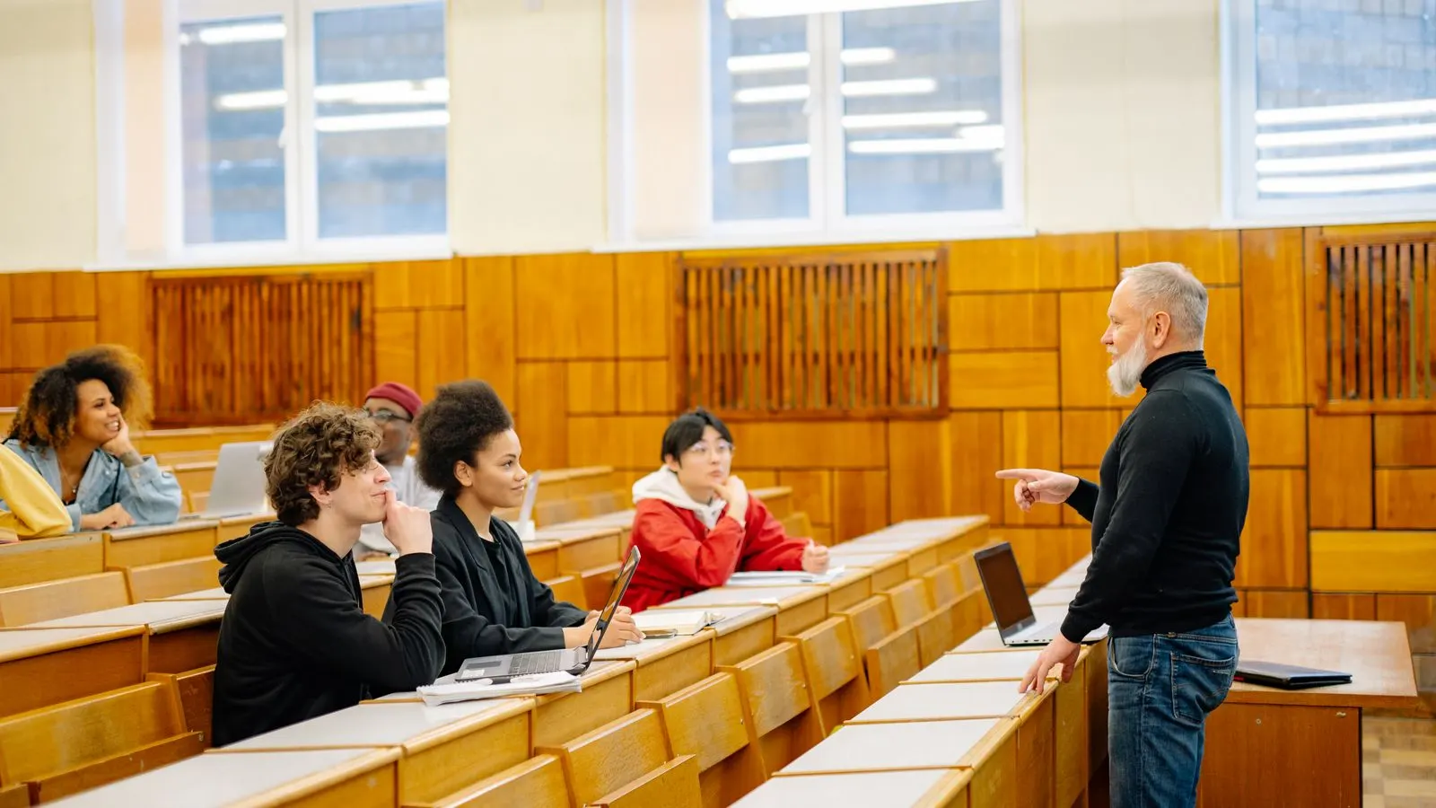 A diverse group of university students engaging with a professor during a classroom lecture.