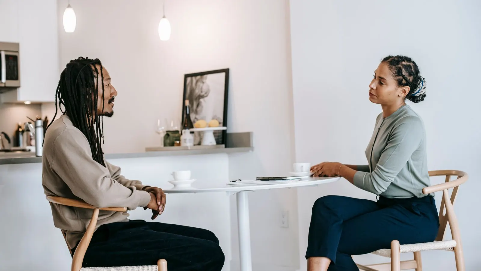 Two people seated at a table talking in a bright room