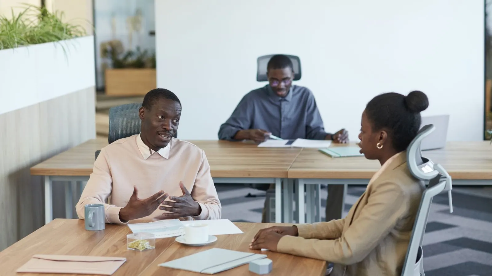 Three professionals engaging in a meeting at an indoor office workspace.